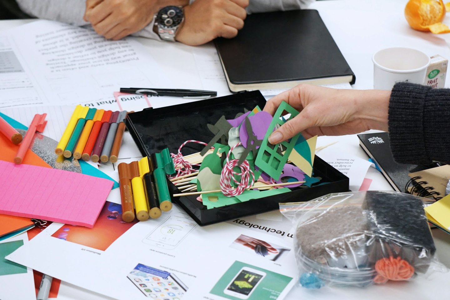 Two people design a mobile app using craft supplies.