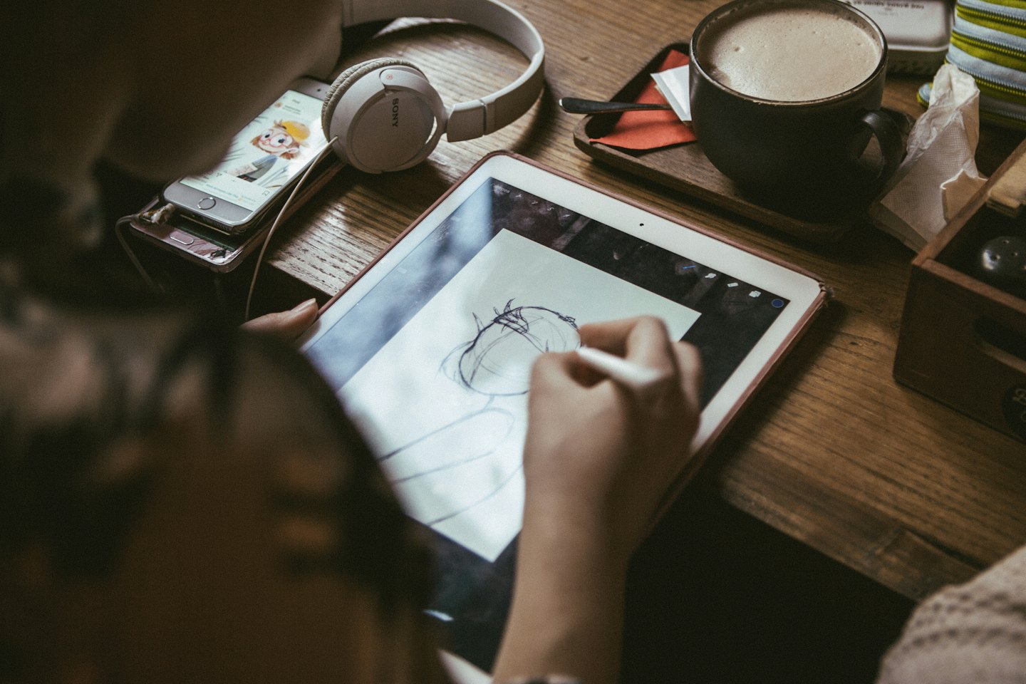 Artist drawing on a digital tablet at a wooden desk.