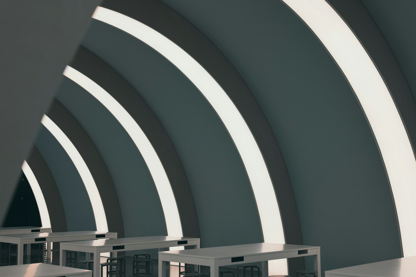 Curved walls with strip lighting and white tables in a modern coworking space.