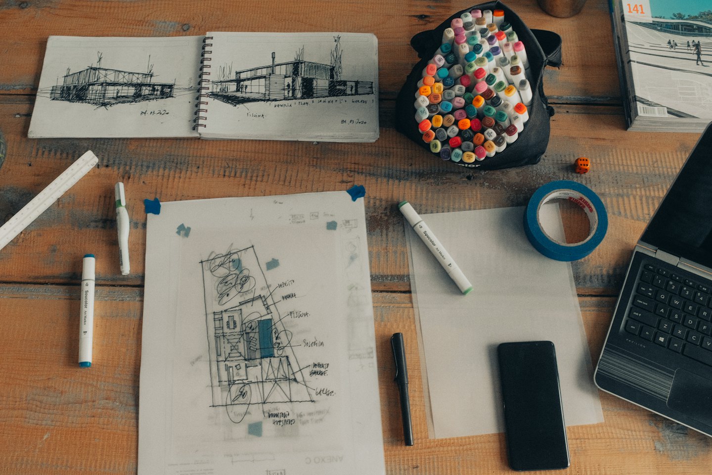 Architectural tools and sketches spread on a wooden desk.