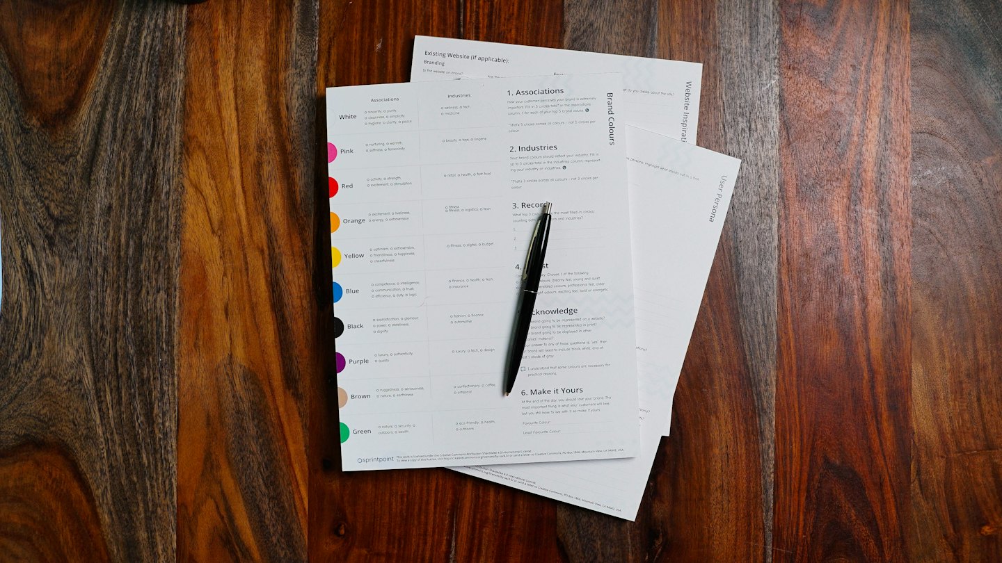 Business branding and website planning documents on a wooden desk.